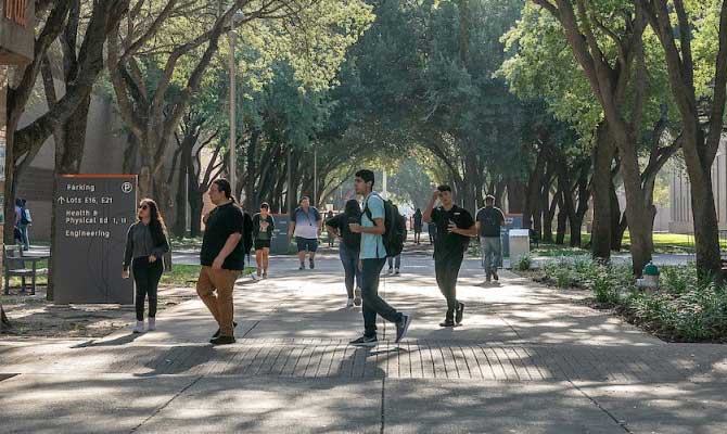 Students walking through the commons of UTRGV, under the shade of trees