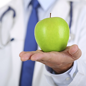 Close up of a doctor's hand holding a green apple, in an offering style