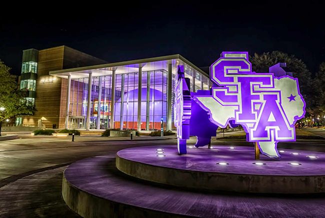 Stephen F Austin commons at light, lit up in purple and white
