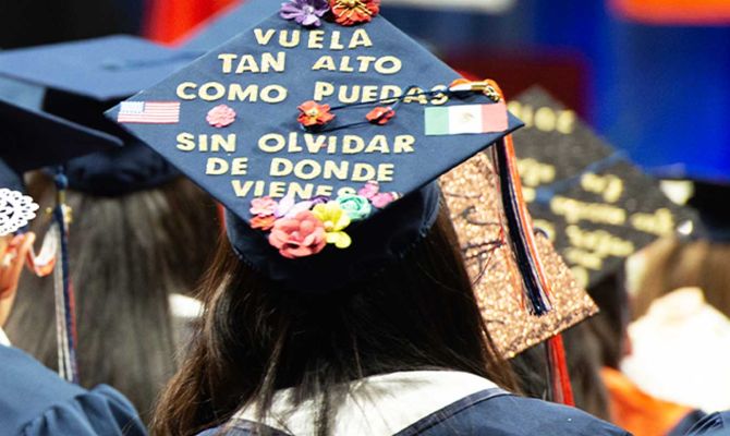 Graduate with a cap and a message on the cap in spanish, translating: don't forget where you came from."