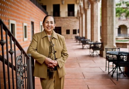 Dr. Juliet V. Garcia standing outdoors near a stair railing. Dressed a work suit ensemble and smiling at the camera